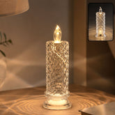 A clear faceted crystal LED candle light glowing warmly on a wooden surface, casting patterned light.