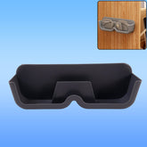 A gray plastic glasses holder is shown with a pair of silver-framed glasses inside, set against a blue background, with an