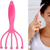 A woman uses a pink plastic scalp massager with five prongs on the side of her head.