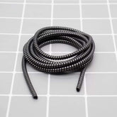 Metallic spiral cable protector guarding a smartphone charging cable.