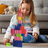 A young girl playing with a tall, colorful structure made from bullet-shaped blocks on a carpeted floor.