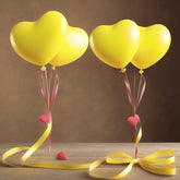 Four bright yellow heart balloons with pink ribbons and small red hearts tied to a yellow bow.