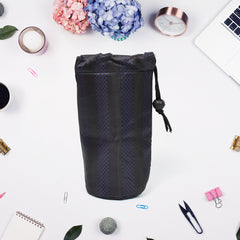 The black patterned pouch lies flat, surrounded by various jewelry items and accessories on a light surface.
