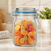 A clear, mason jar-shaped plastic bag filled with colorful gummy candies sits on a white countertop.