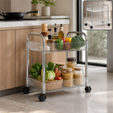 A silver two-tier rolling cart with clear ribbed plastic baskets filled with fresh produce and pantry items in a kitchen.