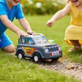 Two children playing with a grey plastic toy SUV car outdoors on a grassy path.