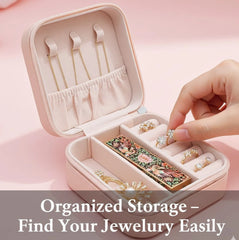 Hand placing a ring into an open pink jewelry box, with a decorative compact inside.