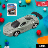 A grey die-cast toy car with a black spoiler sits on a vibrant blue surface surrounded by colorful pom-poms.