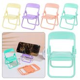 Four miniature foldable chairs in pastel yellow, purple, peach, and teal, with a phone resting on a purple stand.