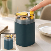 A hand presses the yellow button of a teal automatic toothpick dispenser, releasing a single toothpick. A smaller inset