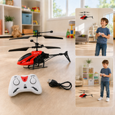 A red and black toy helicopter with a white remote control and USB cable on a wooden floor, with a child playing in the