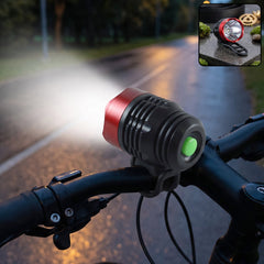 The red and black bicycle headlight casts a bright beam forward on a dark, wet asphalt path.