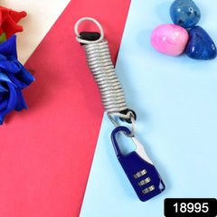A blue carabiner-style combination lock with a silver coiled wire attached, displayed on a pink and blue surface.