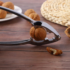Silver metal nutcracker with a walnut in its jaws, presented in blue and clear plastic packaging.