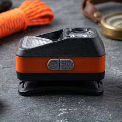 The black and orange headlamp with its patterned strap and a coiled black USB charging cable on a white background.