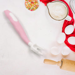 A single pink and white baby fork with a bendable handle, surrounded by baking ingredients.