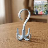 Light blue plastic rotating hanger with four hooks on a wooden table, with a small inset showing it in use.