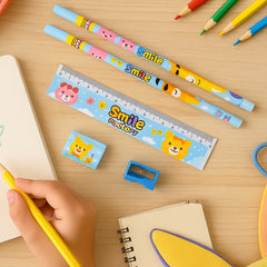 A child's hand holds a yellow pencil, with a stationery set featuring cartoon animals on a wooden desk with other art