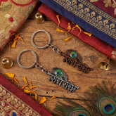 Radhe Radhe metal keychain featuring copper finish and peacock feather design