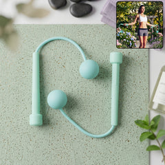 A woman in athletic wear uses a mint green cordless jump rope outdoors in a garden setting.