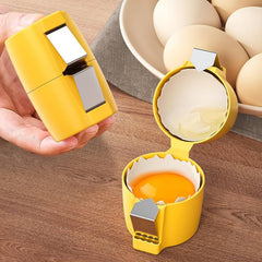 A person's hand holds a closed yellow egg cracker tool, while an open one sits on a wooden surface beside a plate of eggs.