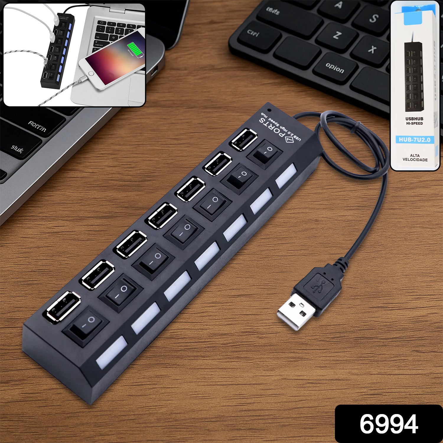 A black 7-port USB hub with individual on/off switches and LED indicators sits on a wooden desk next to a laptop and