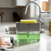 Gray and clear soap dispenser with a yellow sponge, filled with green liquid, on a kitchen counter.