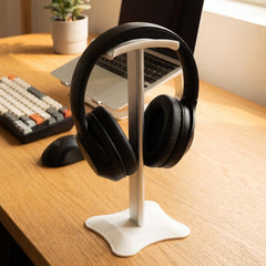 White metal headphone stand with a square base on a plain white background.