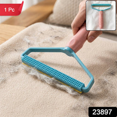 A person's hand holds a pink and blue lint remover, actively cleaning a beige fabric surface covered in pet hair.