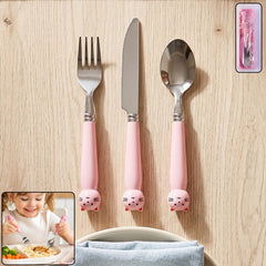A pink cat-themed fork, knife, and spoon are displayed on a light wooden surface.