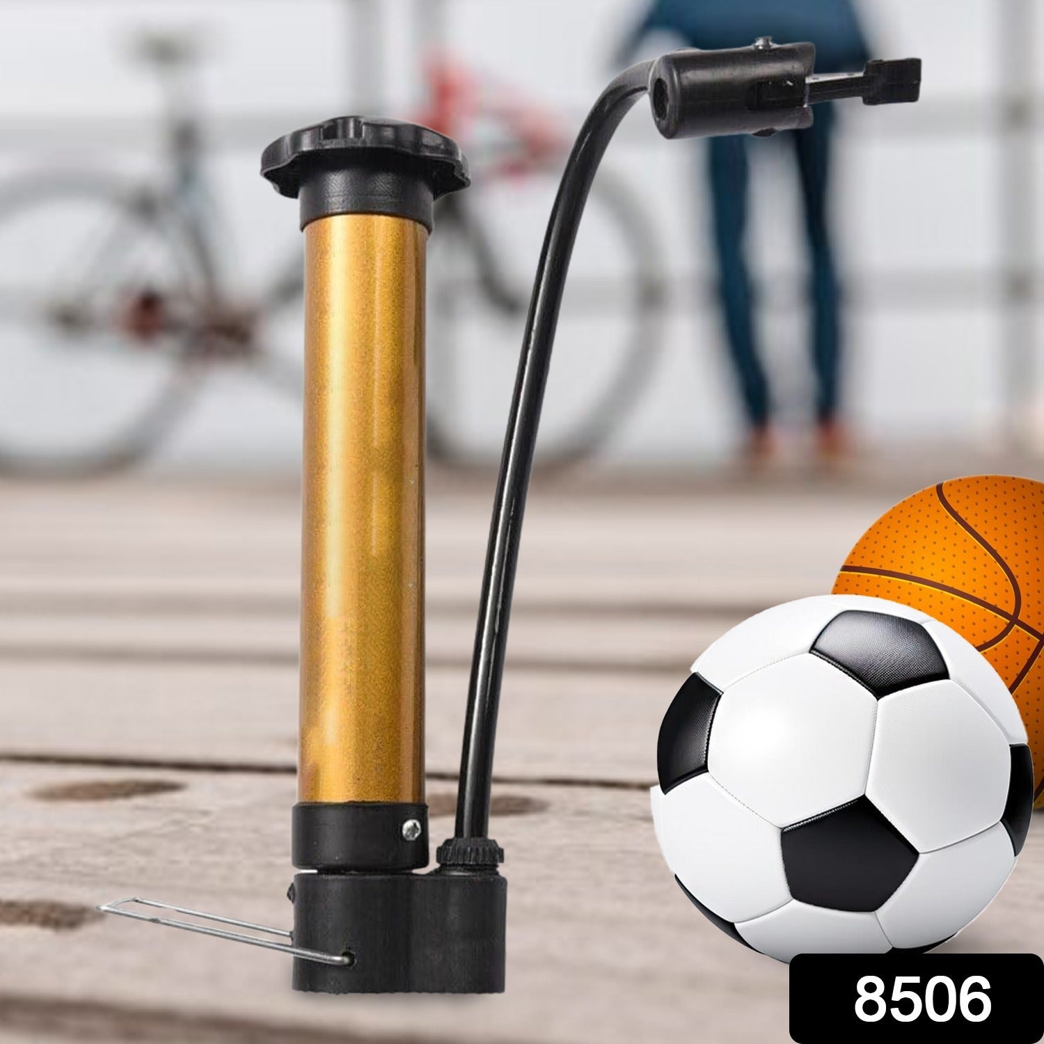 A gold and black hand pump stands upright next to a soccer ball and basketball on a wooden surface.