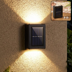 A black solar wall light with a blue panel, casting bright light on a beige wall at night.