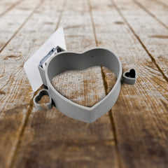 The gray heart-shaped holder with two small heart accents, positioned on a rustic wooden surface.