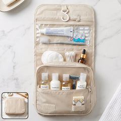 The beige toiletry bag is shown open with a white hook, holding a toothbrush, toothpaste, small bottles, and cotton pads.