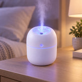 A small white humidifier with blue light and mist on a wooden nightstand beside a bed.