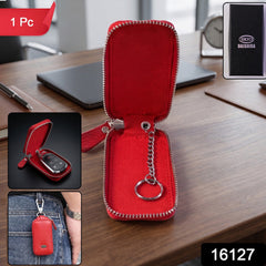 An open red leather key pouch with a silver chain and ring, displayed on a wooden desk with insets showing a key inside and
