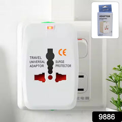 A white universal travel adapter with red outlets and a glowing orange indicator light is plugged into a wall socket.