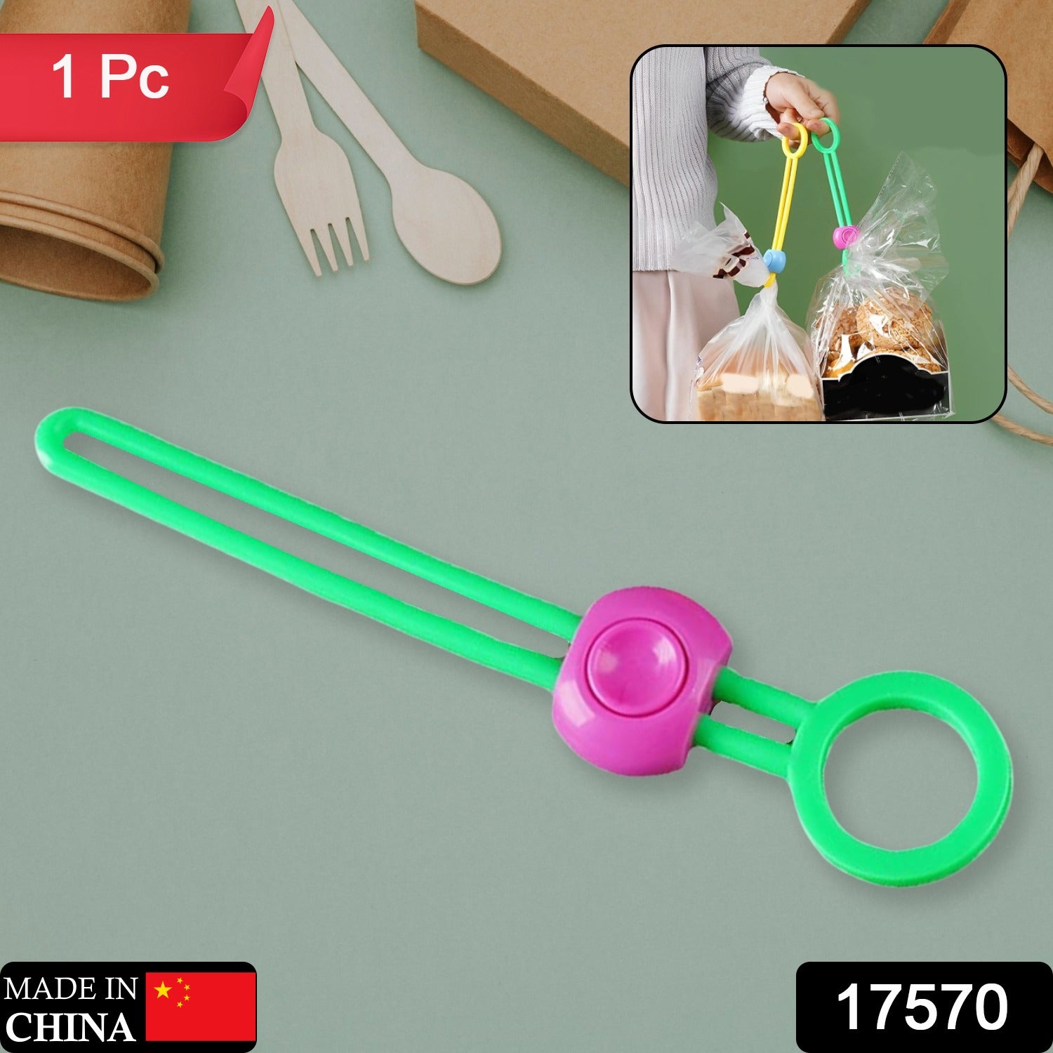 A vibrant green silicone bag clip with a pink button closure, featuring a ring on one end, displayed on a grey surface. The