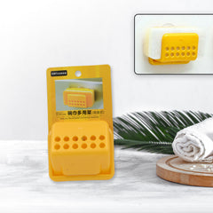 A hand places a white rectangular sponge into a yellow plastic holder attached to a tiled wall.