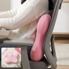 A pink, bone-shaped lumbar support cushion rests on a marble surface with decorative white stones and green leaves.