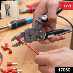 A person's hands using a gray and black crimping tool on a red insulated wire end, with other connectors nearby.