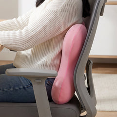 A pink, bone-shaped lumbar support cushion is displayed on a plain white background.