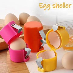 Three colorful egg cracker tools—pink, orange, and yellow—are displayed on a wooden surface alongside several whole eggs.