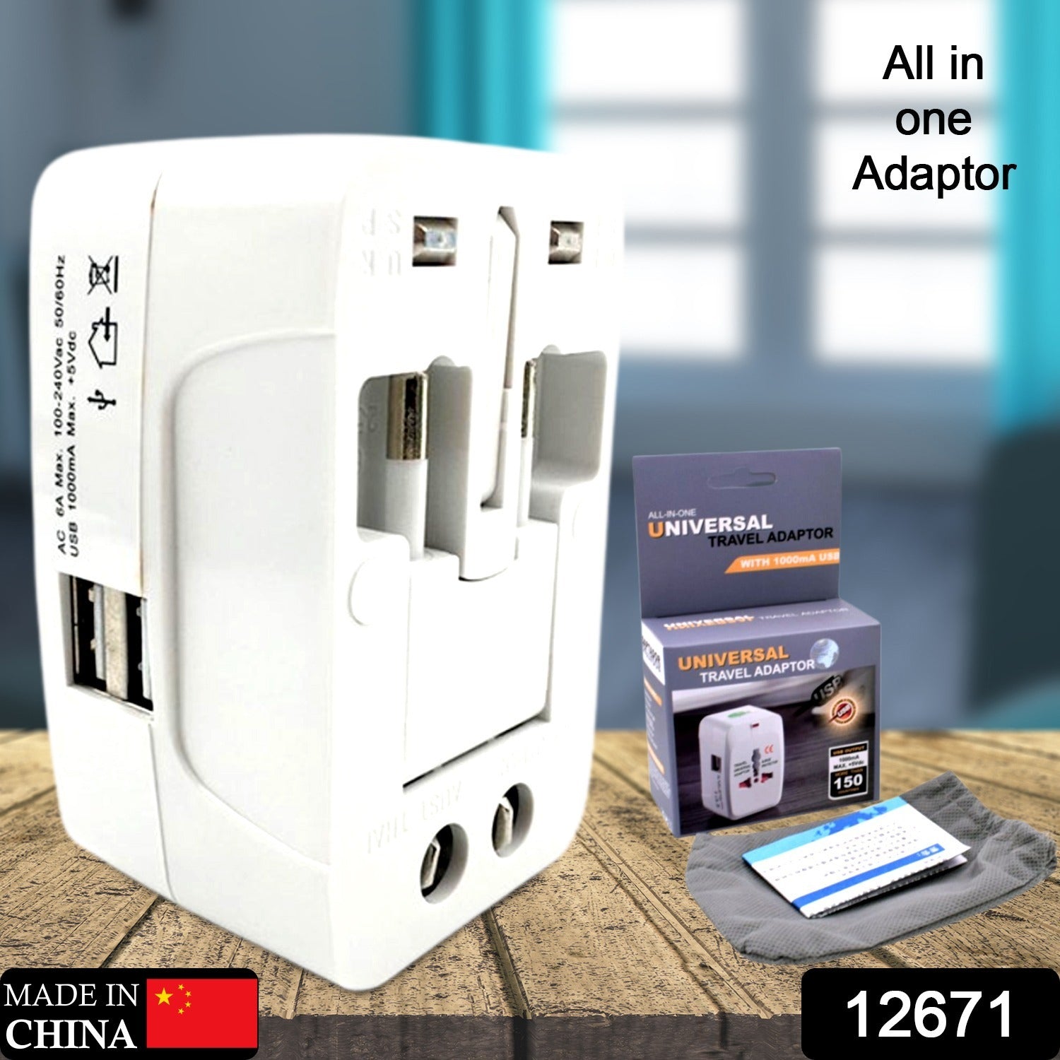 White universal travel adapter with its box, instruction booklet, and a gray pouch on a wooden surface.