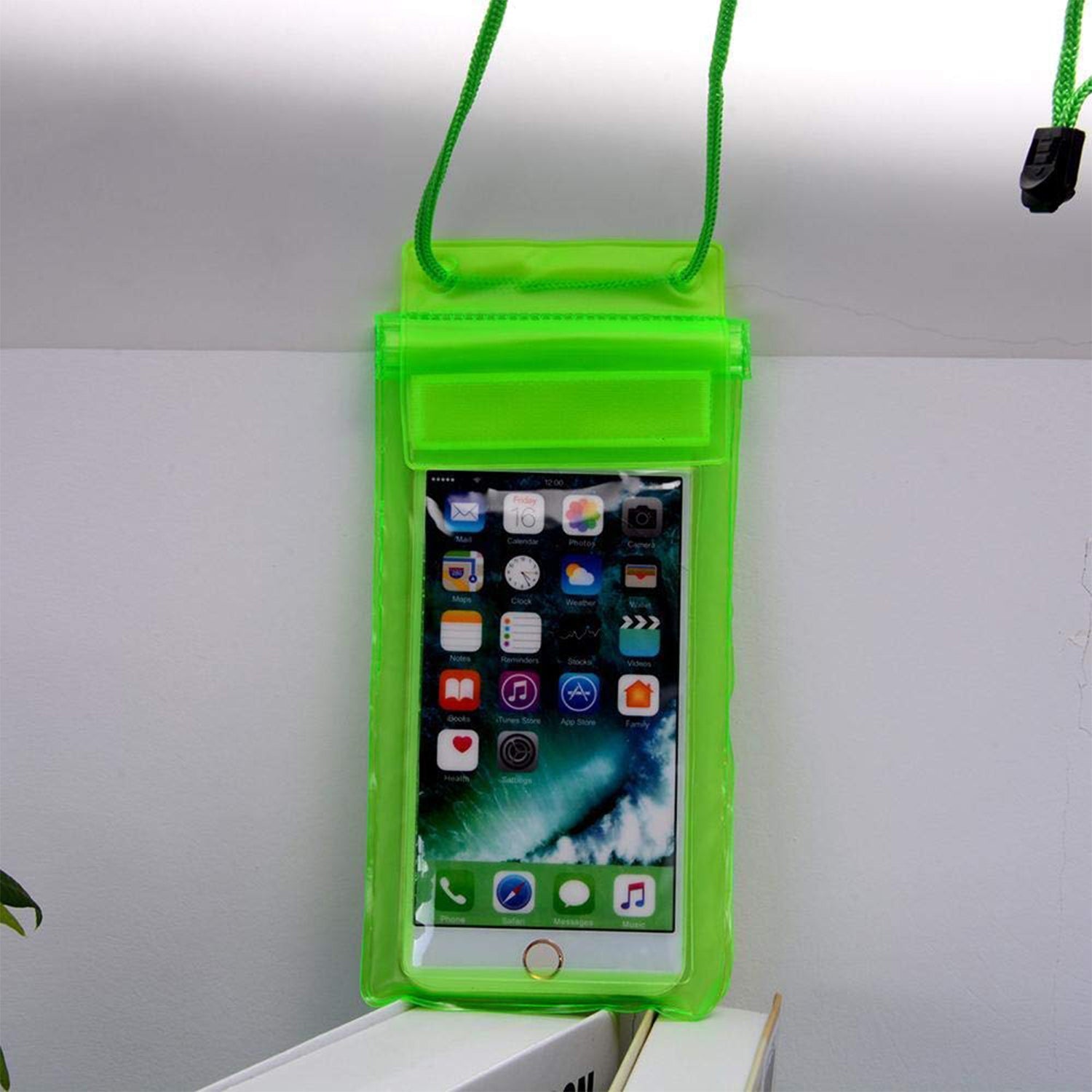 Neon green waterproof phone pouch with a phone inside, hanging against a light-colored wall.