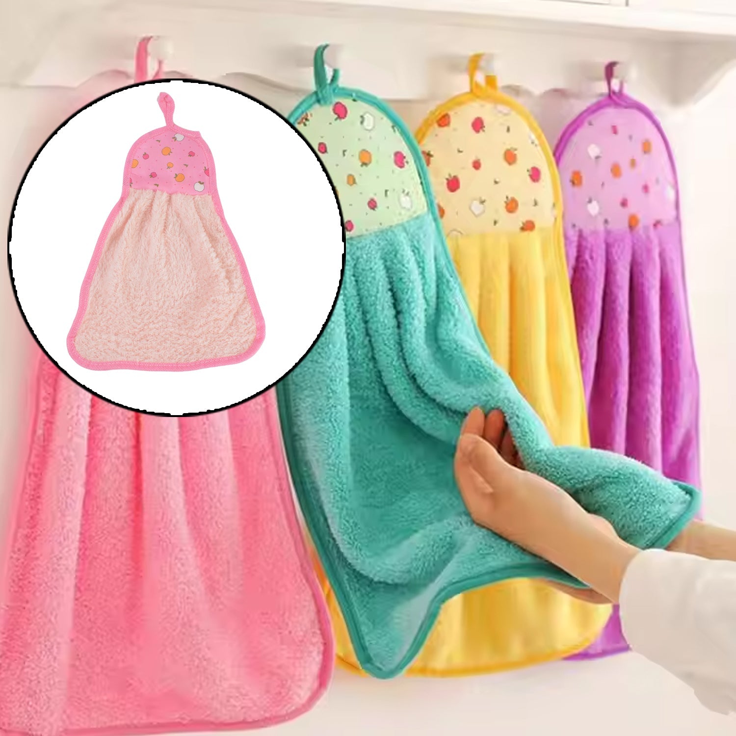 A hand holds a teal microfiber towel with a fruit print top, hanging among other colorful towels on hooks in a kitchen.