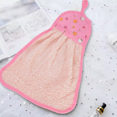 A pink microfiber hand towel with a fruit print top and hanging loop rests on a starry white surface with an open book and