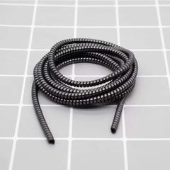 Metallic spiral cable protector guarding a smartphone charging cable.