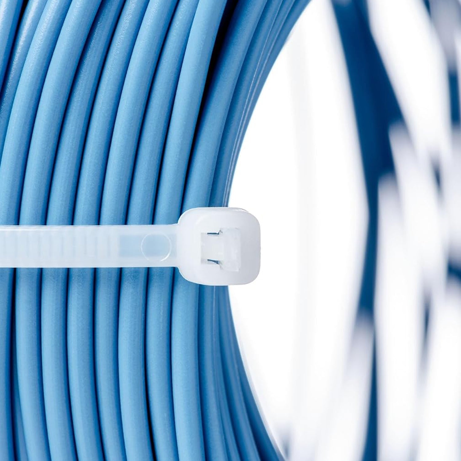 A close-up of a white nylon cable tie securing a coil of light blue electrical cable.