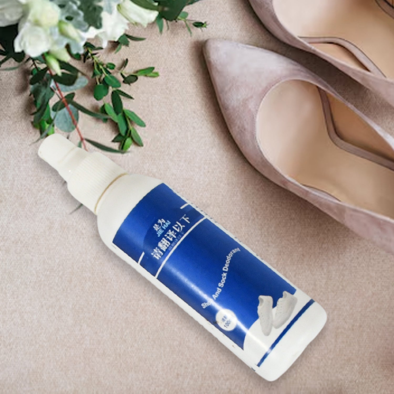 A white and blue bottle of shoe and sock deodorant lies on a light brown textured surface next to a pair of nude high heels